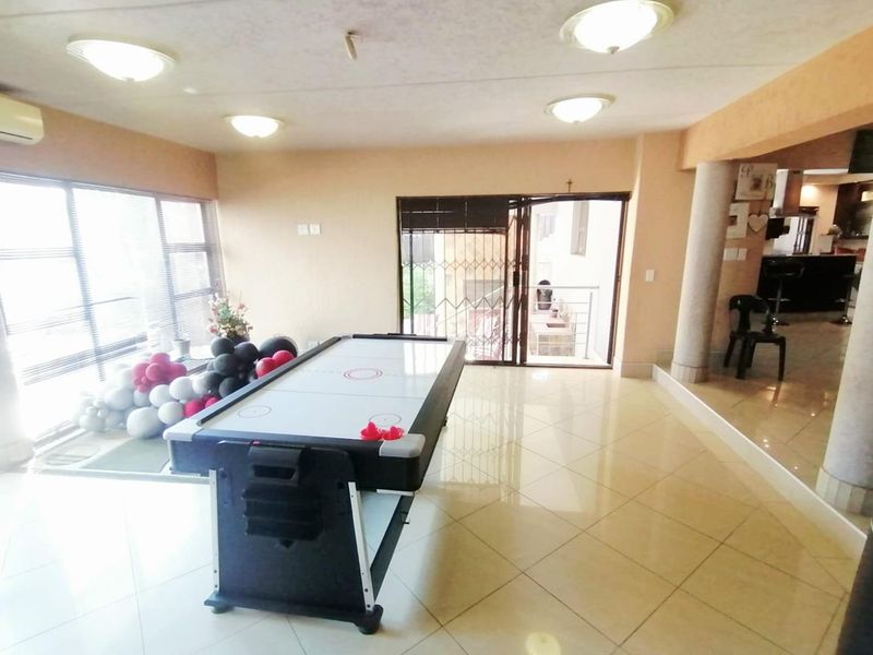 Spacious open-plan living area featuring tiled floors, recessed lighting, and direct access to an outdoor patio through sliding glass doors.