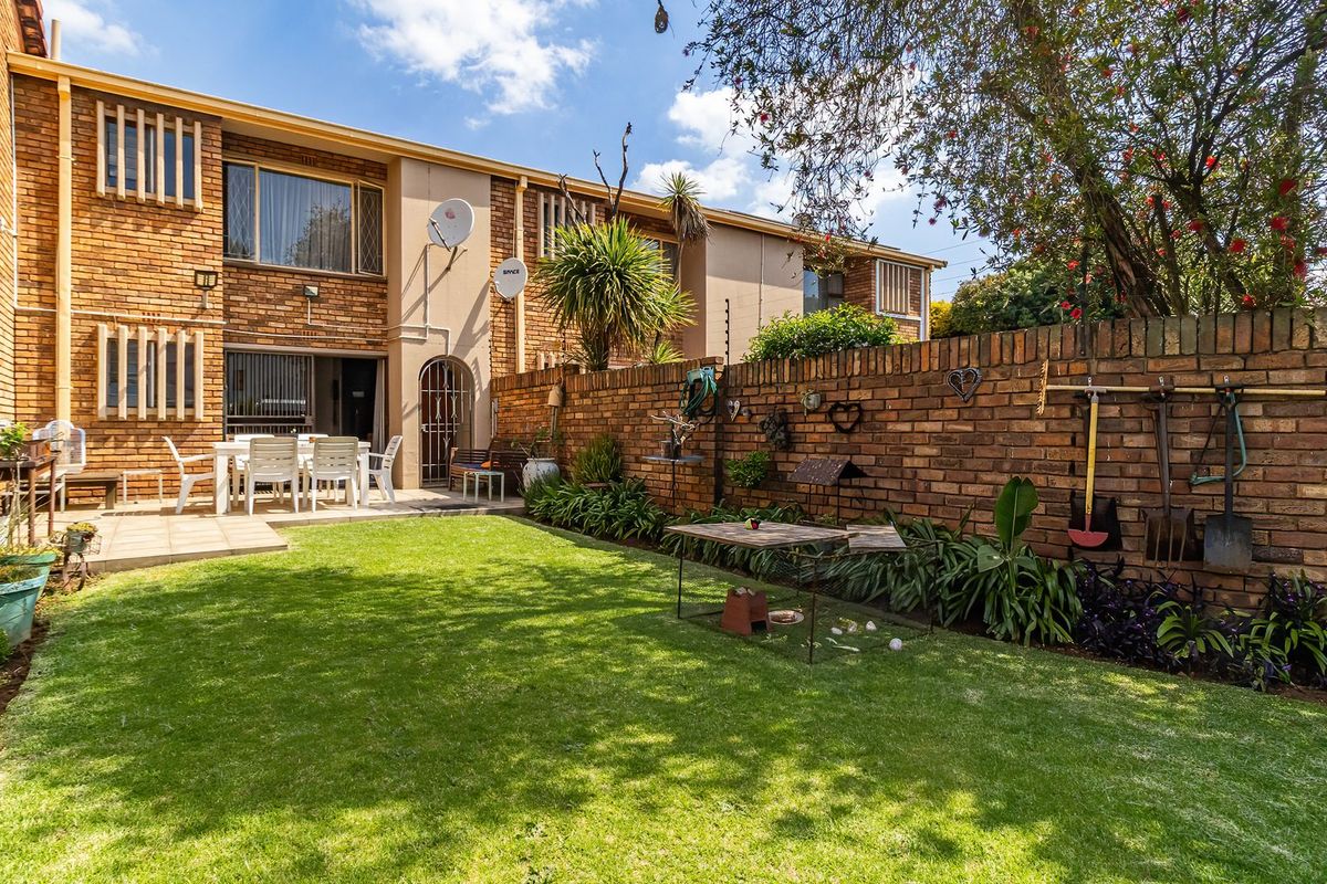 A private rear garden featuring a paved patio area, a well-maintained lawn, and a high brick boundary wall for added privacy.