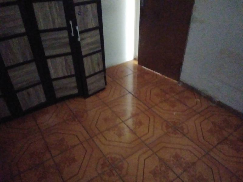 A bedroom featuring tiled flooring and a built-in wardrobe, showing signs of wear and wall staining.