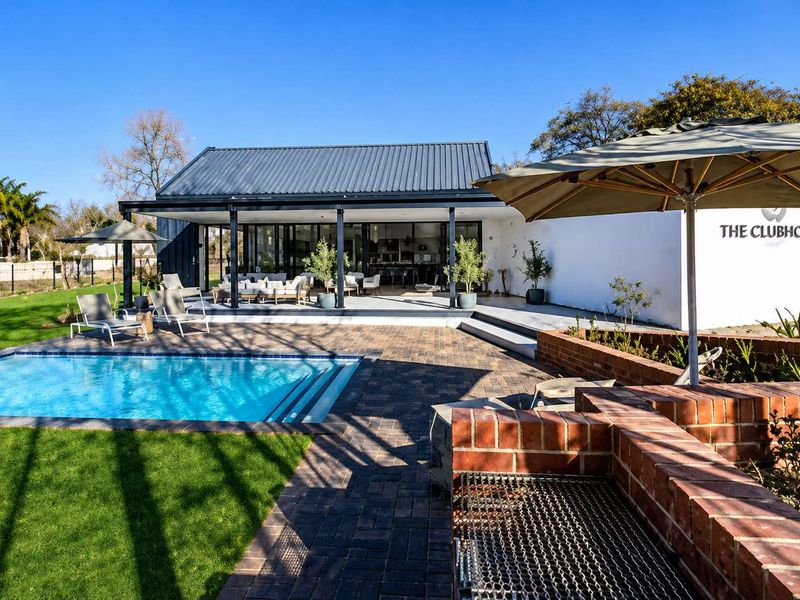 Modern clubhouse facility featuring a swimming pool, paved patio area, and built-in brick braai, perfect for outdoor entertaining and community gatherings.