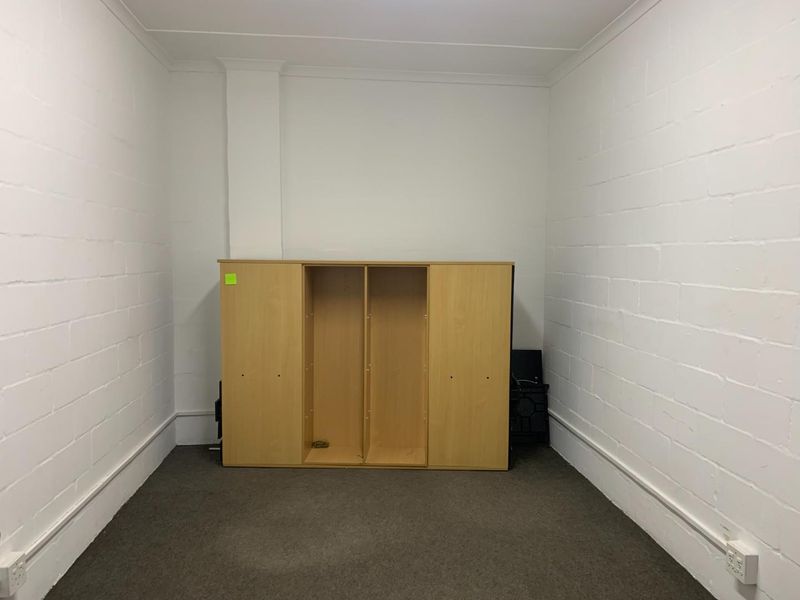 A simple, empty utility space featuring painted brick walls and carpeted flooring, suitable for storage or a functional workspace.