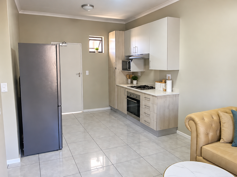 Modern open-plan kitchen featuring light wood cabinetry, built-in oven and hob, and sleek tiled flooring, seamlessly integrated with the living area.