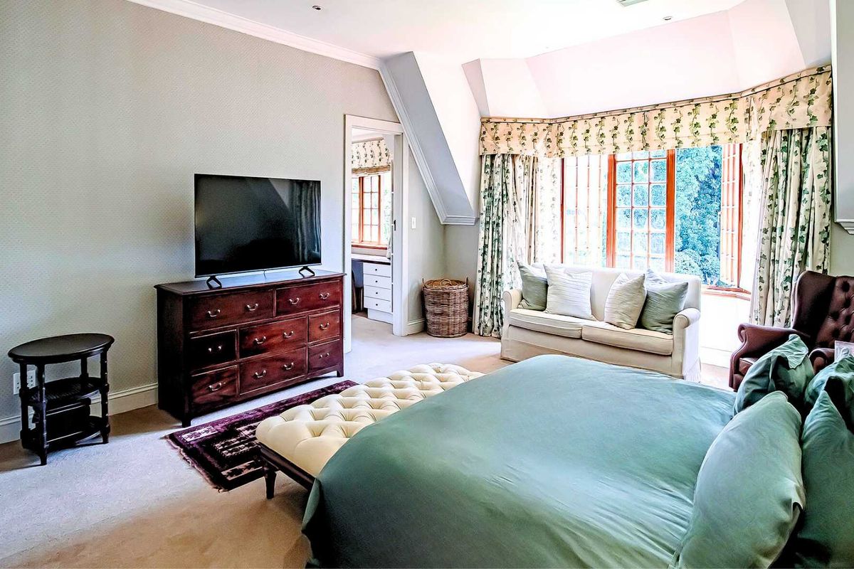 Spacious bedroom featuring a large bay window with garden views, neutral carpeting, and an adjoining walk-in dressing area or study.