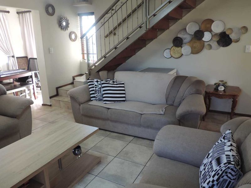A living room area featuring tiled flooring and a staircase with a decorative wrought iron balustrade.
