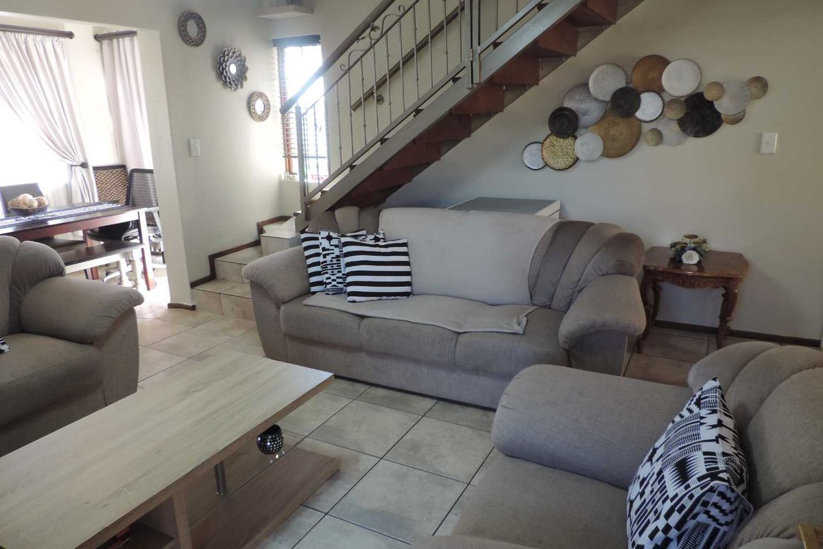 A living room area featuring tiled flooring and a staircase with a decorative wrought iron balustrade.