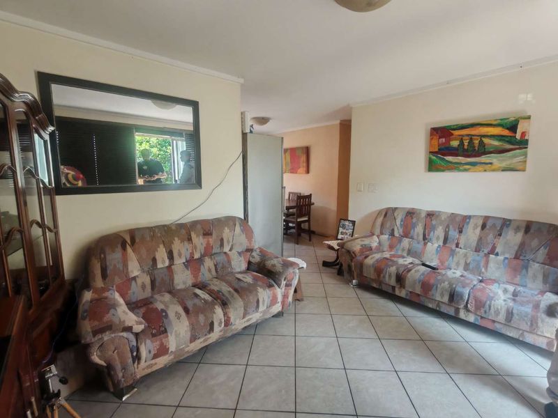 A living room area featuring ceramic floor tiles and coving, currently showing signs of dated finishes and exposed electrical wiring.