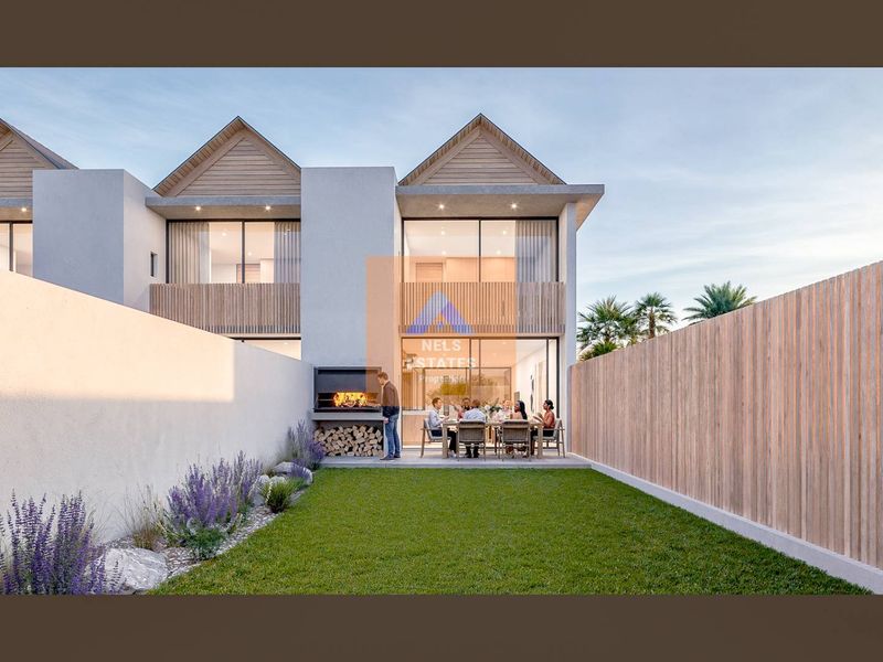 Rear exterior view of a modern townhouse featuring a private garden, paved patio area, and a built-in braai.