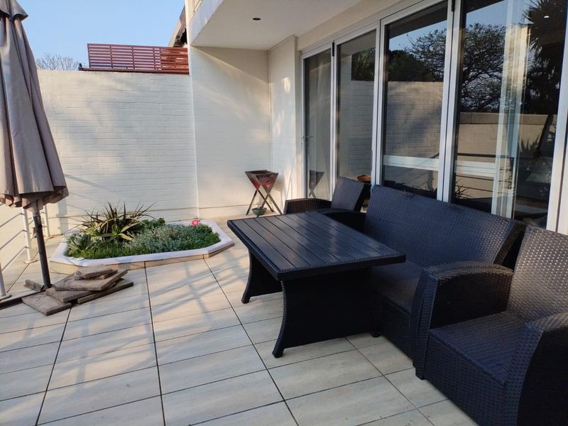 A covered patio area featuring tiled flooring, recessed lighting, and large sliding glass doors providing seamless access to the interior living space.