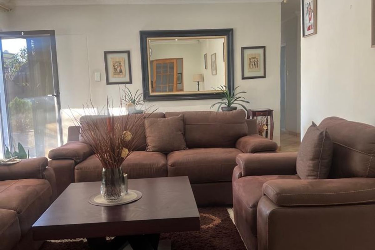A comfortable living room featuring tiled flooring, a beaded ceiling with recessed lighting, and a sliding glass door providing access to the exterior.