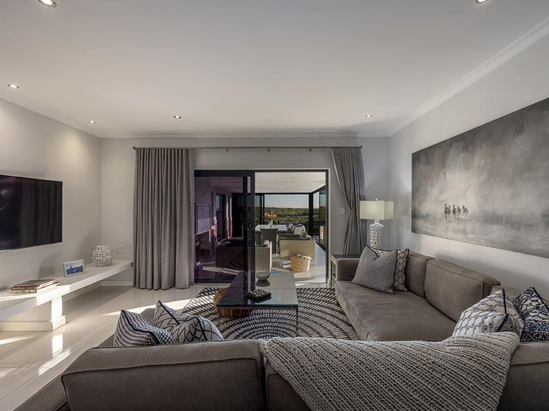 Modern living room featuring recessed lighting, sleek tiled floors, and large sliding glass doors that open to an outdoor patio area.