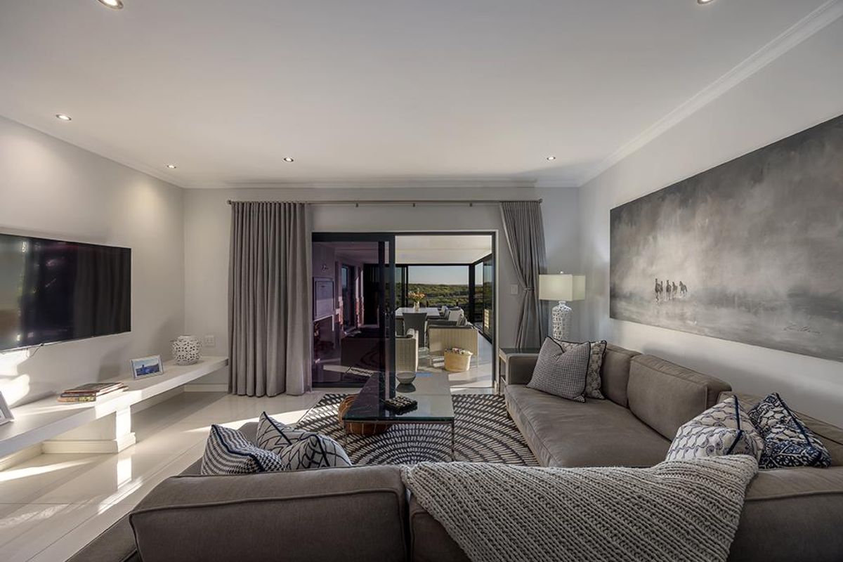 Modern living room featuring recessed lighting, sleek tiled floors, and large sliding glass doors that open to an outdoor patio area.