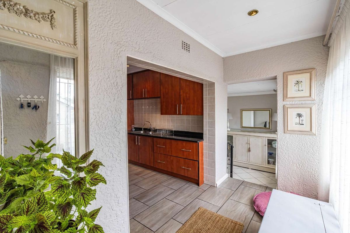 A functional kitchen featuring warm-toned wooden cabinetry, dark stone countertops, and neutral tiled flooring, providing a clean and practical workspace.