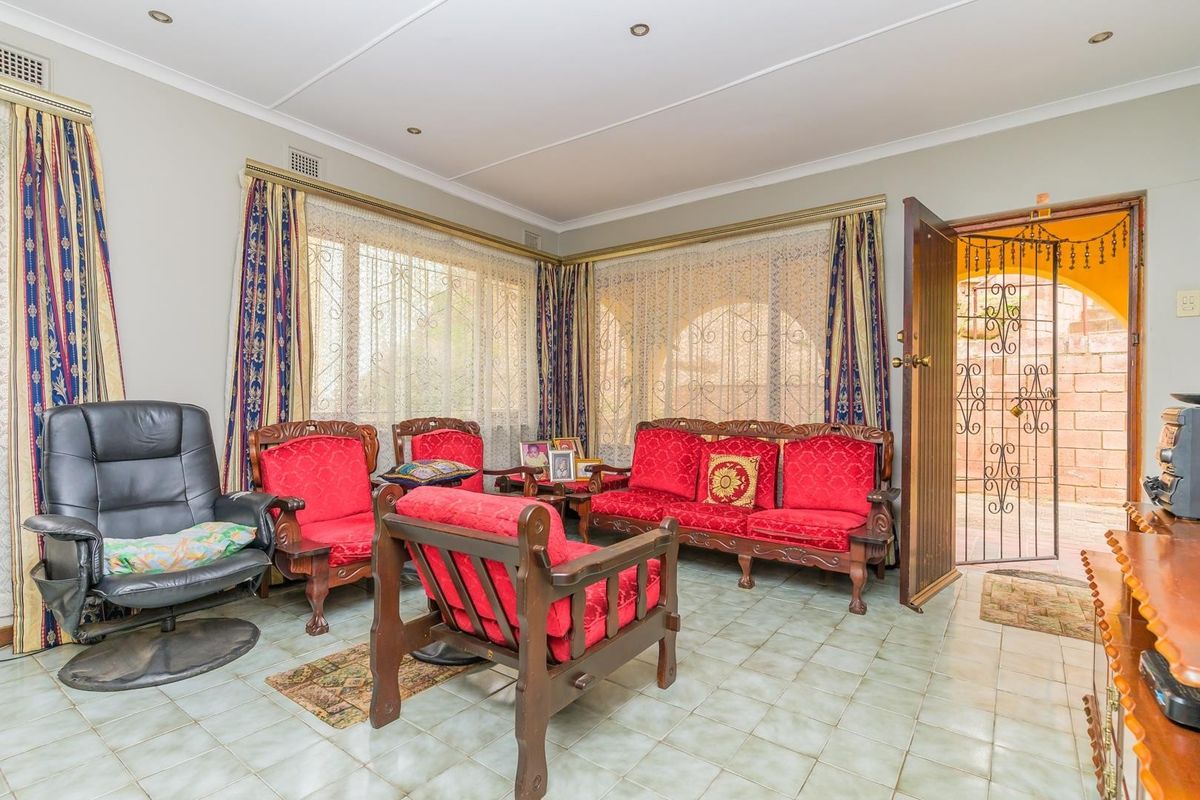 A living room featuring tiled flooring, recessed downlights, and direct access to an outdoor area through a security gate.