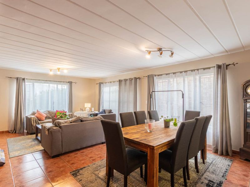 Spacious open-plan living and dining area featuring tiled flooring, tongue and groove ceiling, and large windows allowing for ample natural light.