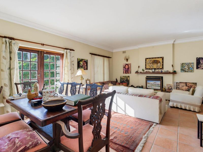 Open-plan living and dining area featuring terracotta floor tiles, a fireplace with a wooden mantel, and French doors leading to the garden.