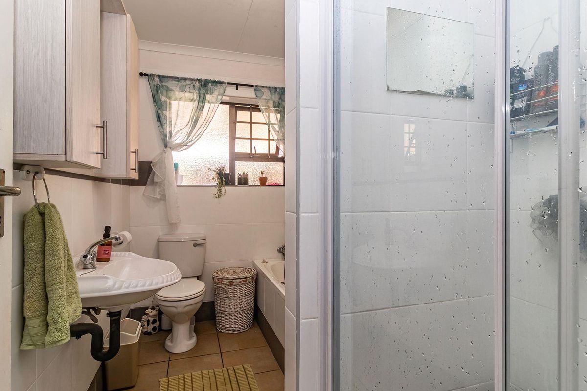 Functional bathroom featuring a shower enclosure, pedestal basin, toilet, and built-in wall cabinetry with tiled finishes throughout.