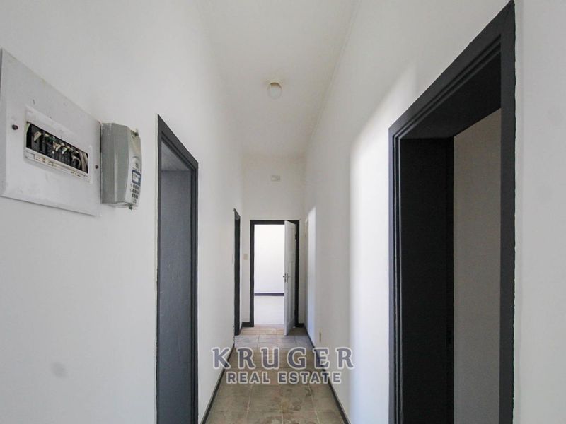 A narrow interior hallway featuring tiled flooring and access to multiple rooms, with a visible electrical distribution board mounted on the wall.