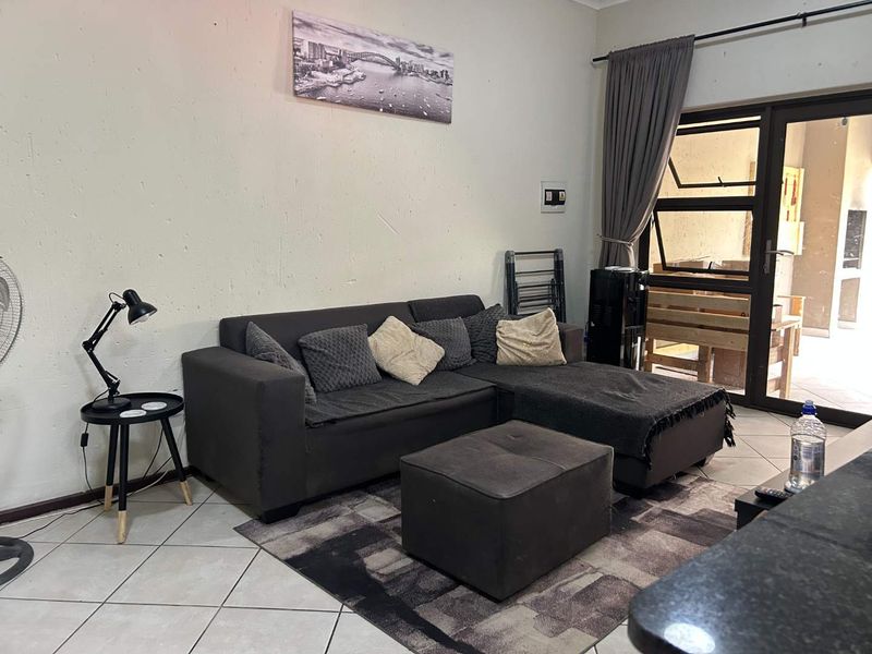 A living room area featuring tiled flooring and an aluminium sliding door leading to an outdoor space.