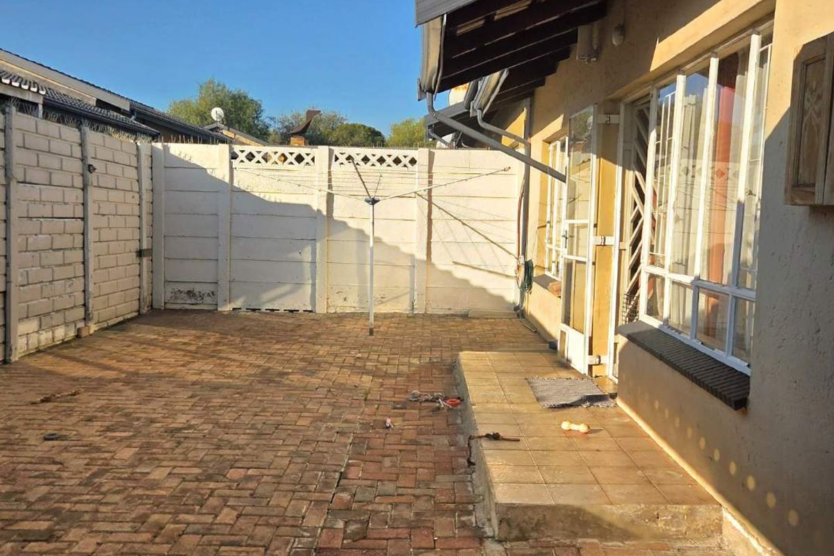 A private rear courtyard featuring paved flooring, a raised tiled step, and perimeter boundary walls with a built-in washing line.