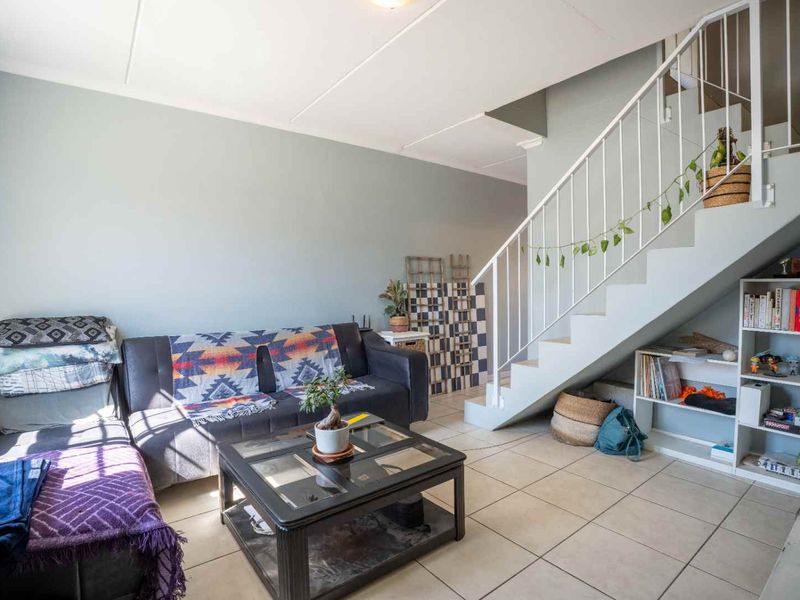 A living room area featuring tiled flooring and an open staircase with integrated under-stair storage space.