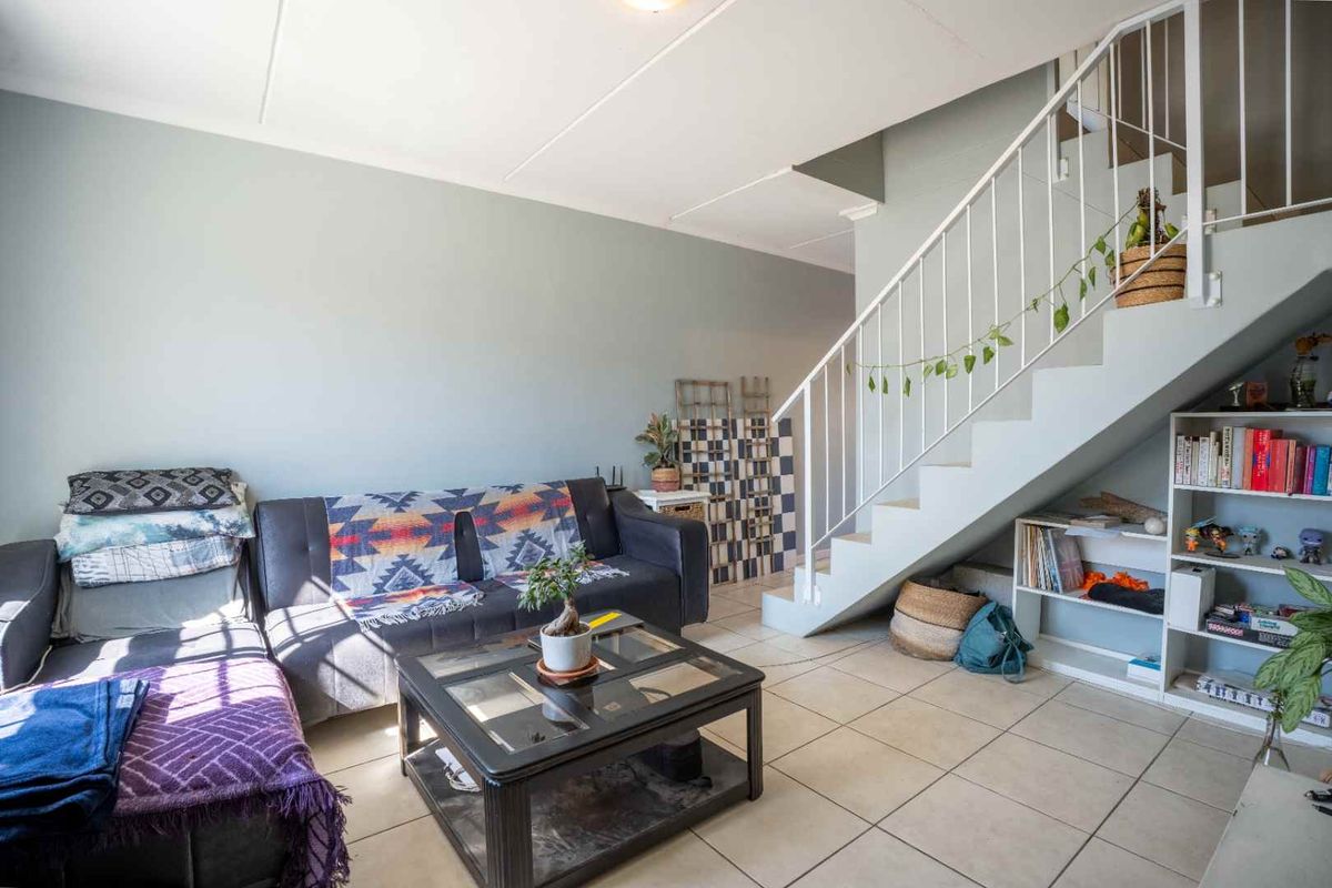 A living room area featuring tiled flooring and an open staircase with integrated under-stair storage space.