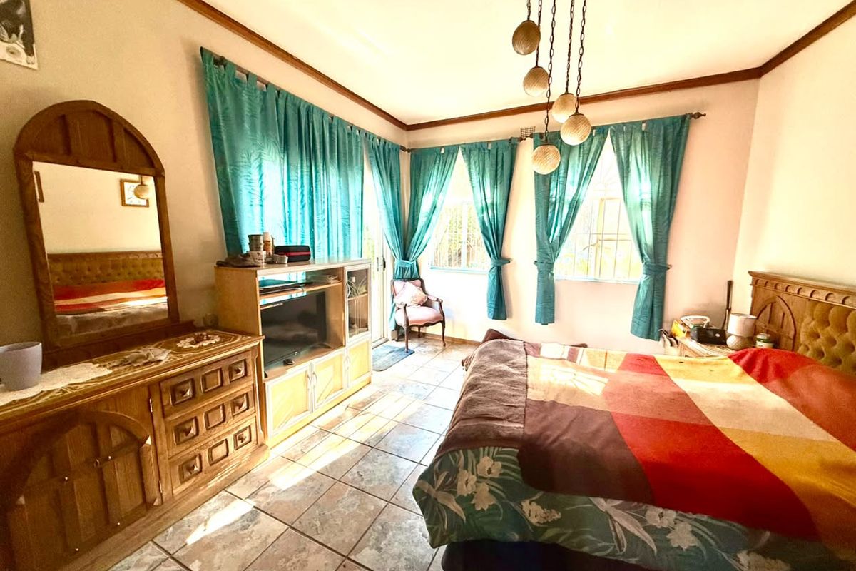 A spacious bedroom featuring tiled flooring, large windows with natural light, and a decorative pendant light fixture.