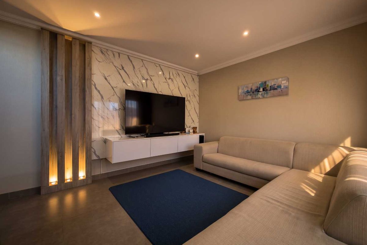 Modern living room featuring a marble-look feature wall, integrated timber slat paneling with accent lighting, and a sleek floating media console.