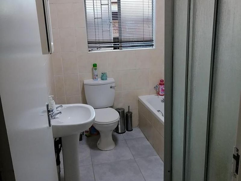 A functional bathroom featuring a pedestal basin, toilet, bathtub, and a separate shower enclosure with tiled finishes.