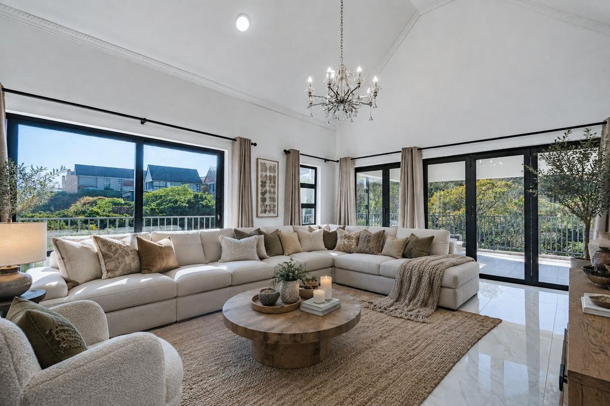 Spacious living room featuring a vaulted ceiling, crown molding, polished tile floors, and large sliding glass doors that provide abundant natural light.