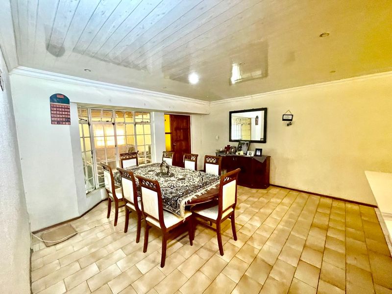 A dining room featuring tiled flooring, a glossy tongue and groove ceiling, and steel-framed windows, offering a functional space for family meals.