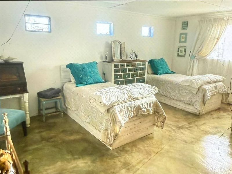A bedroom featuring polished concrete flooring and high-level clerestory windows, providing a rustic aesthetic suitable for a farm property.