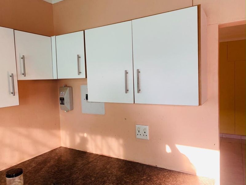A functional kitchen area featuring white upper cabinetry, dark laminate countertops, and visible electrical infrastructure, ready for cosmetic updates.