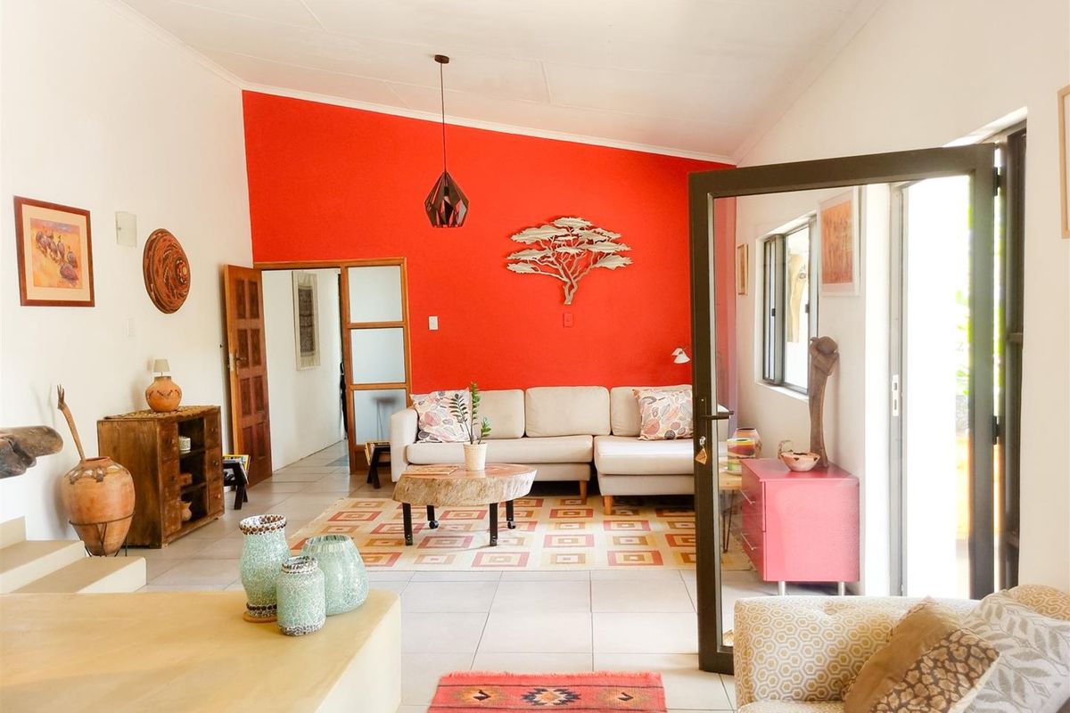 Spacious living room featuring a striking red accent wall, tiled flooring, and large glass doors providing access to the outdoor area.
