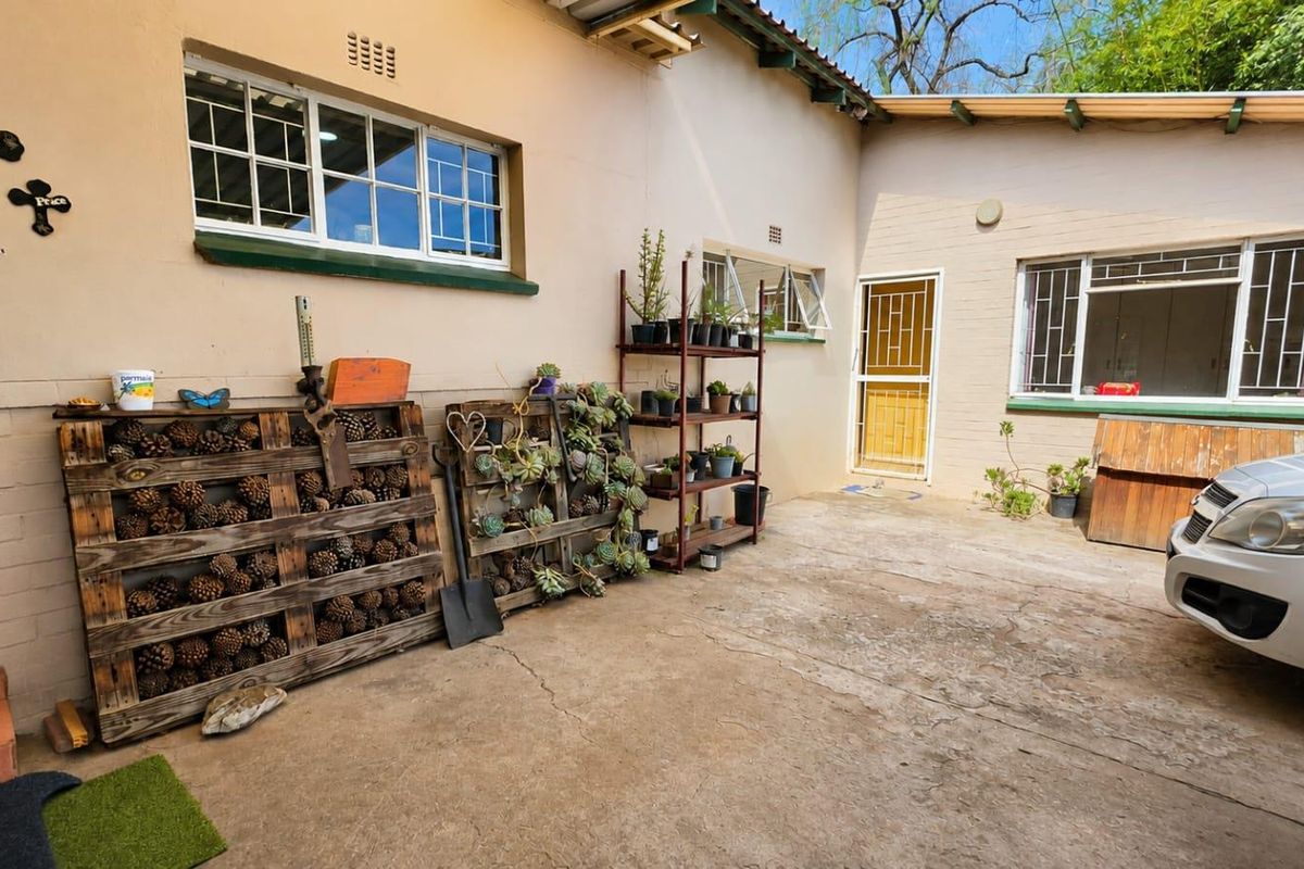 A paved rear courtyard area featuring brick masonry walls, steel-framed windows, and a security gate, providing functional outdoor space.