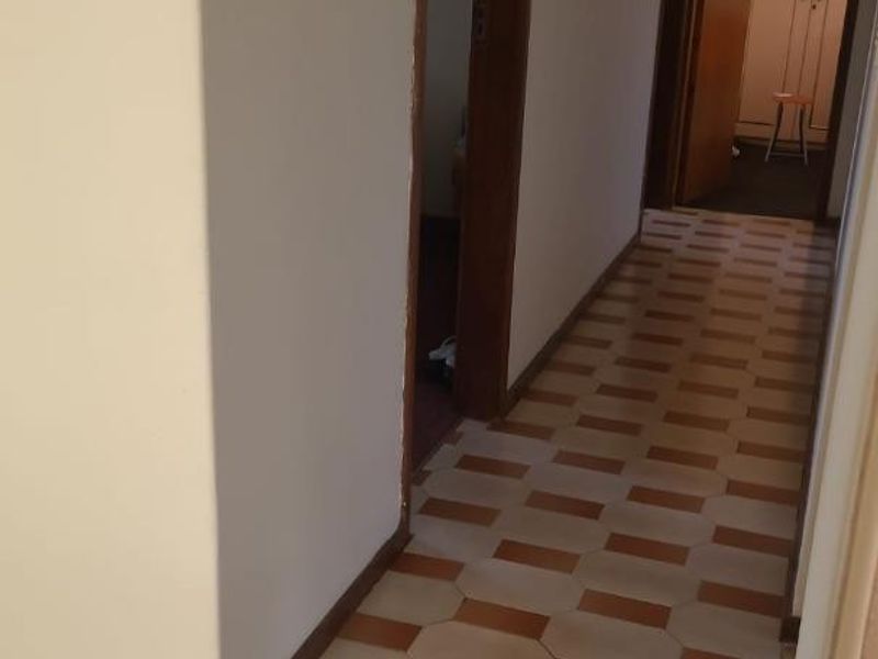 A functional hallway featuring traditional tiled flooring and access to adjacent rooms, providing a neutral foundation for interior updates.