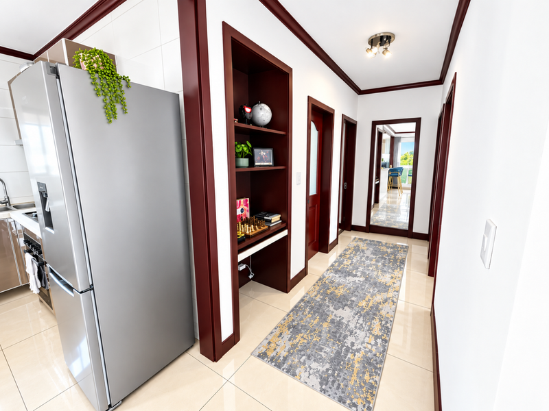 A bright hallway featuring tiled flooring, dark wood trim, and built-in shelving, leading towards an open-plan living area.