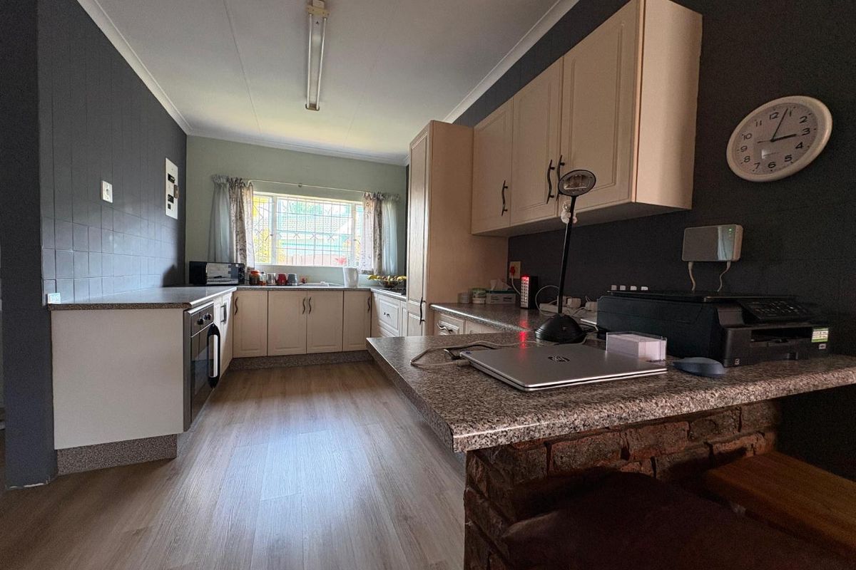 A functional kitchen featuring light-toned cabinetry, granite-look countertops, a built-in oven, and a breakfast bar area with a brick base.