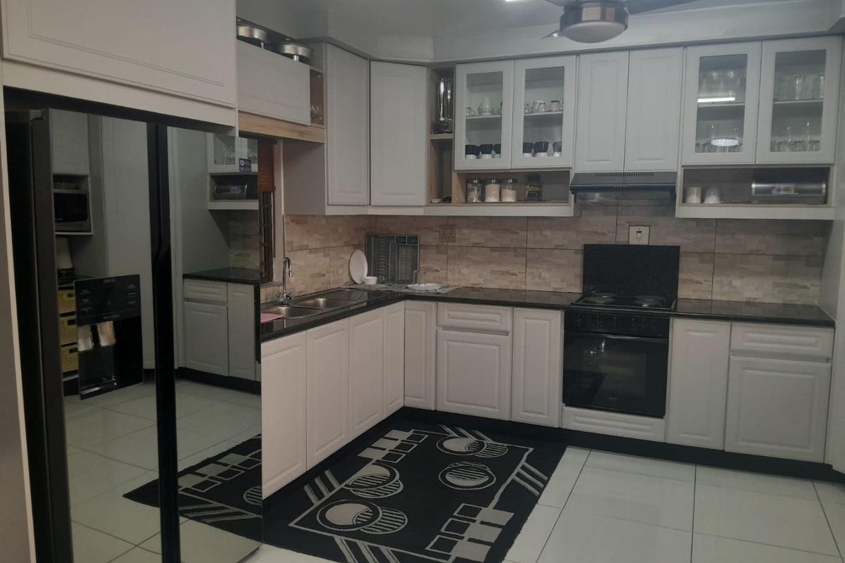 A well-maintained kitchen featuring white cabinetry, dark stone countertops, integrated oven and hob, and a tiled backsplash.