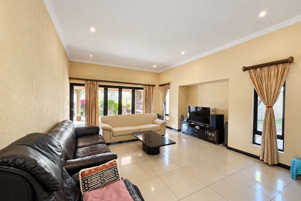 Spacious living room featuring large porcelain floor tiles, recessed downlighting, and sliding glass doors providing direct access to the outdoor area.