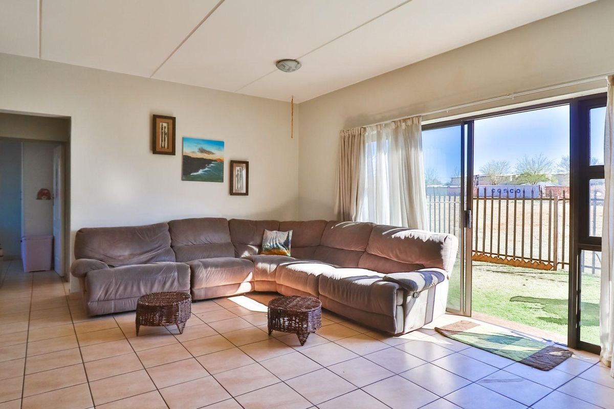 A spacious living room featuring tiled flooring and large sliding glass doors that provide direct access to the outdoor area.