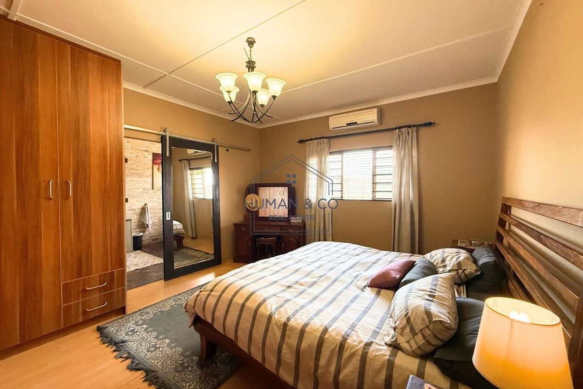A well-maintained bedroom featuring built-in wooden cabinetry, a sliding barn-style mirror door, and a wall-mounted air conditioning unit.