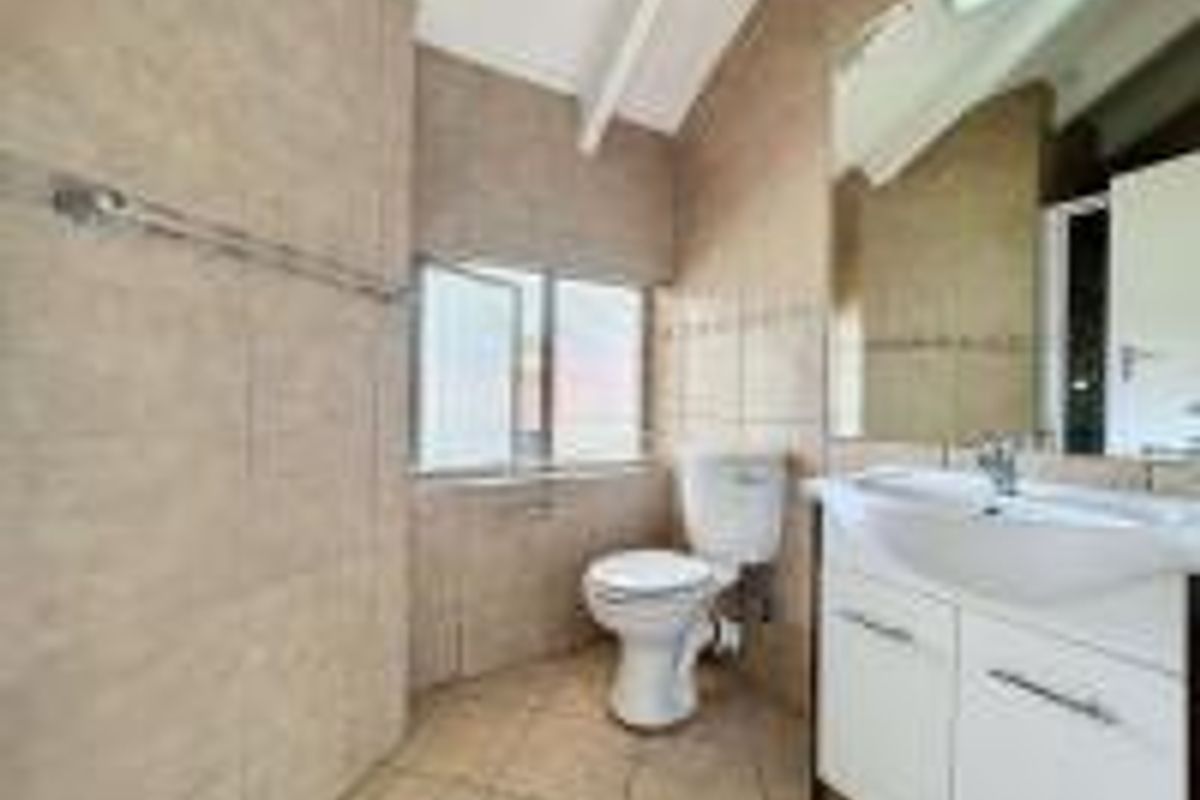 A functional bathroom featuring tiled walls and flooring, a white vanity cabinet with a washbasin, and a wall-mounted mirror.