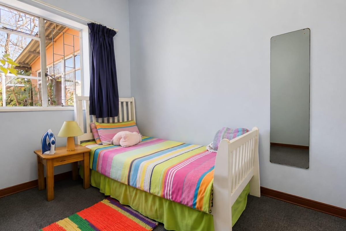 A functional bedroom featuring carpeted flooring, a window with security bars, and neutral wall finishes.