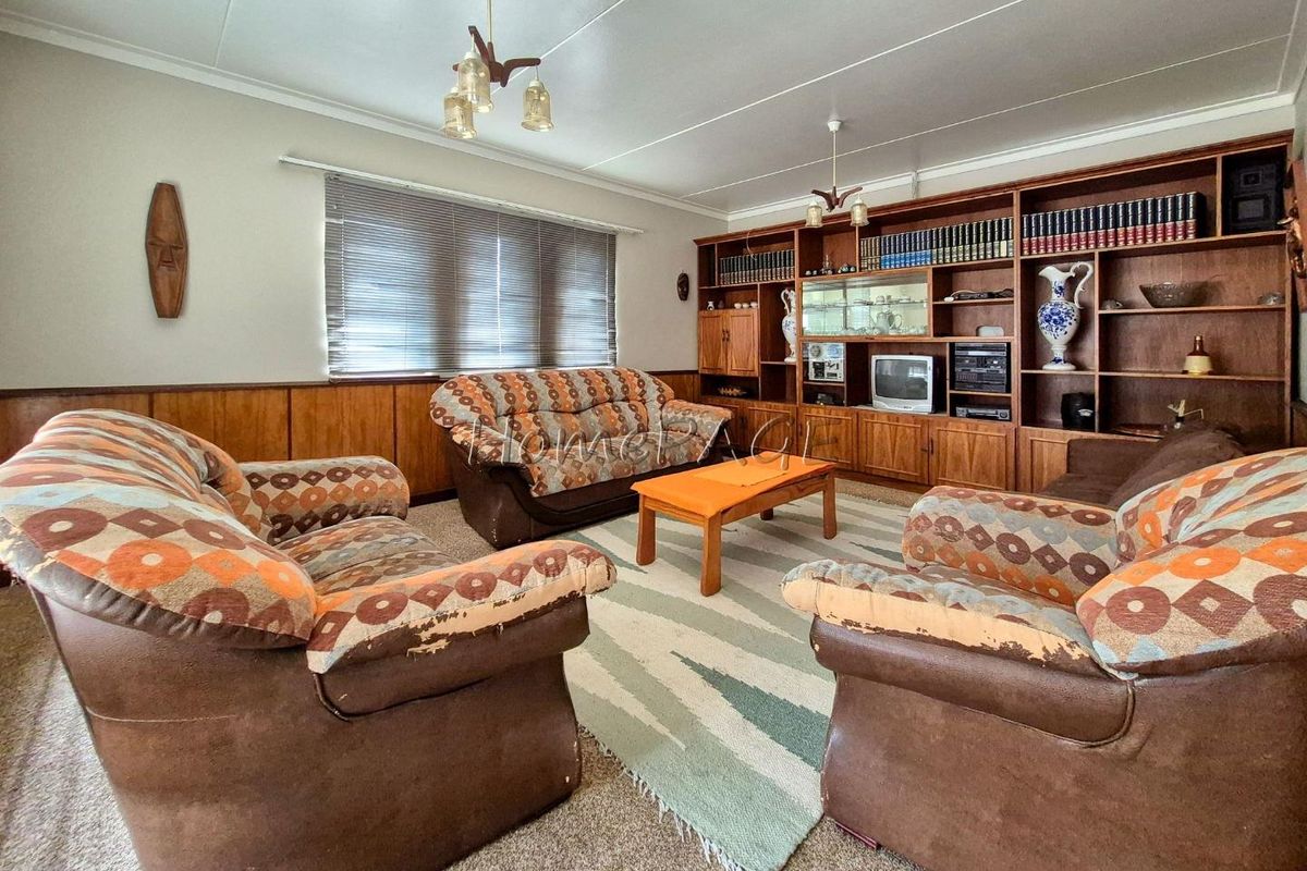 A spacious living room featuring built-in wooden cabinetry and wall paneling, offering a classic layout with ample storage space.
