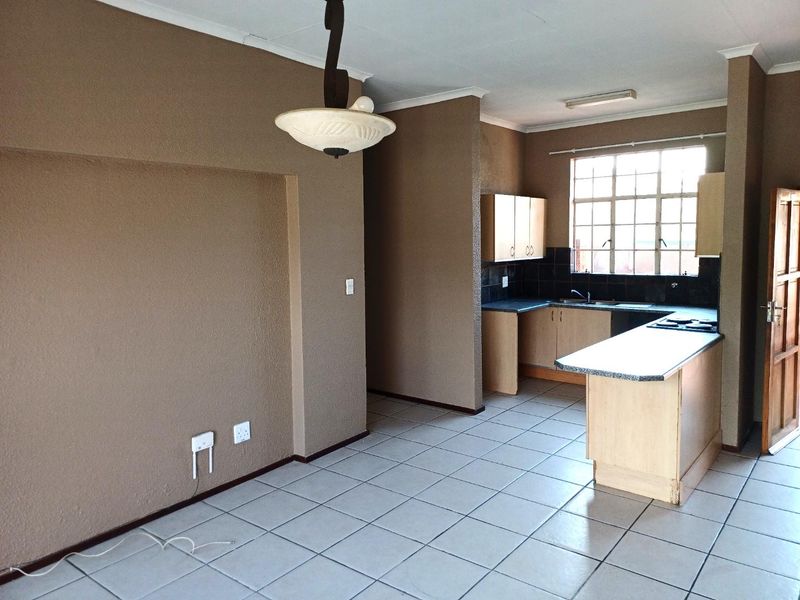 Open-plan living and kitchen area featuring tiled flooring, built-in cabinetry, and a functional kitchen layout with a built-in hob and sink.
