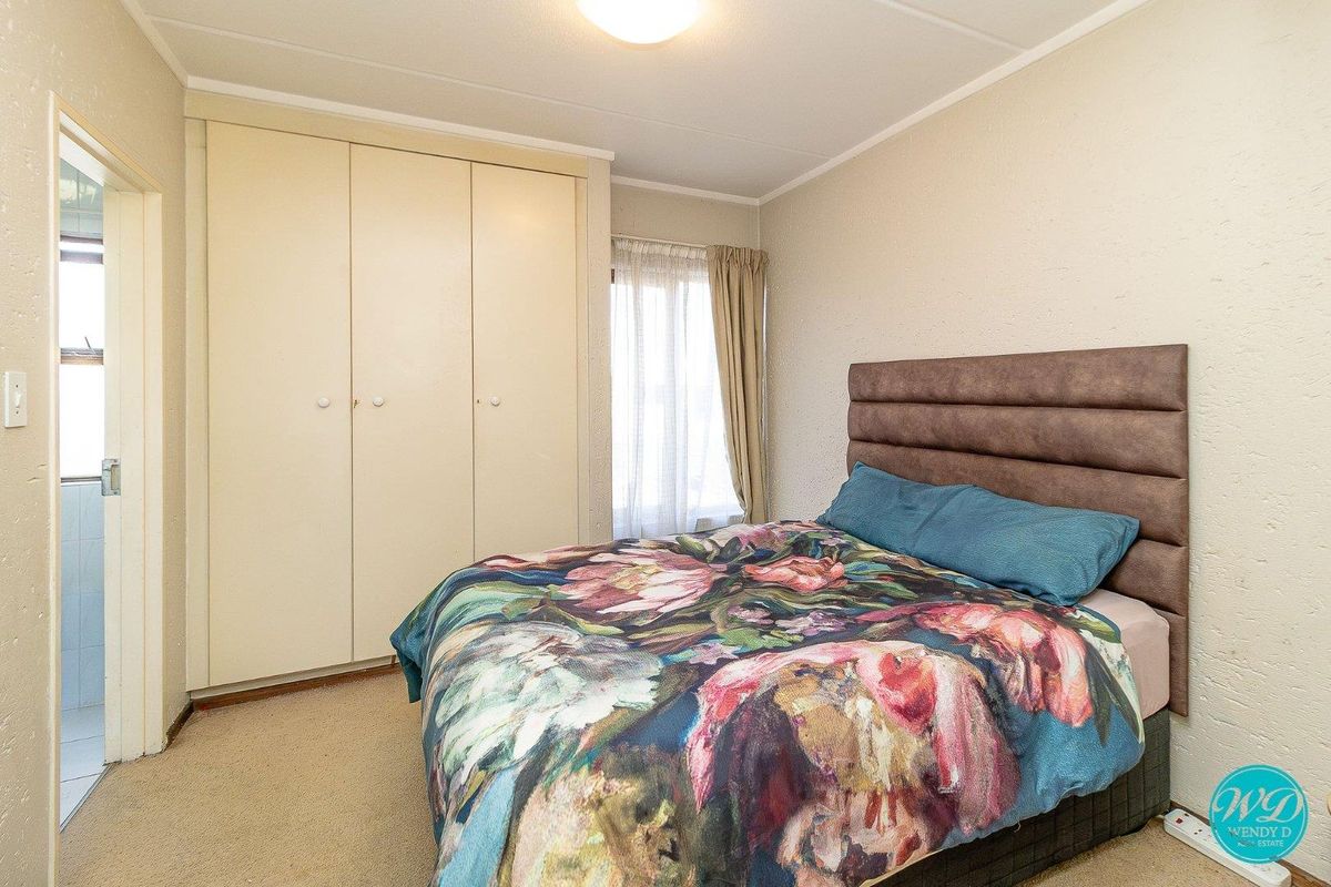 A functional bedroom featuring built-in wardrobes, neutral wall finishes, and carpeted flooring, providing a comfortable and practical living space.