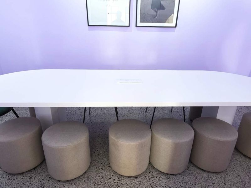 A modern office meeting space featuring a large central table and polished concrete flooring, suitable for collaborative work environments.