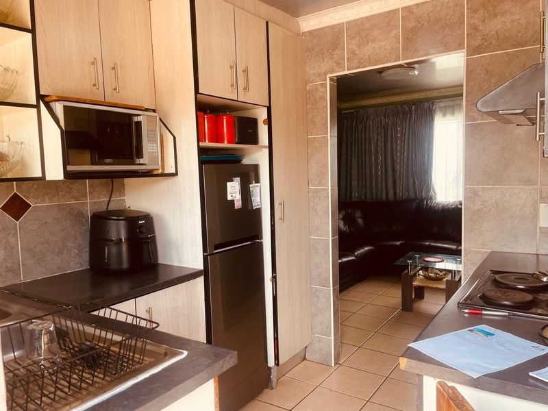 Functional kitchen featuring built-in cabinetry, laminate countertops, integrated hob, and extractor fan, with direct access to the adjacent living area.