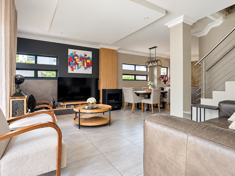 Spacious open-plan living and dining area featuring a modern built-in fireplace, recessed ceiling details, and a contemporary staircase with stainless steel balustrades.