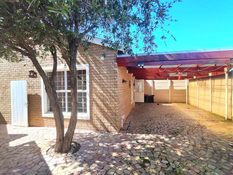 Rear exterior area featuring a brick facade, paved patio, and a timber pergola, providing a functional outdoor space.